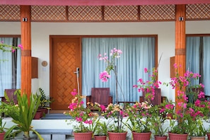 A traditional Japanese-style entrance with a wooden door, potted plants, and a bamboo lattice.