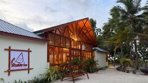 A beachside building with a wooden structure, a swing, and a signboard.