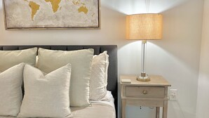 A neatly made bed with white linens and pillows, a world map artwork on the wall, and a bedside table with a lamp. - Large and Rare 4-bedroom apartment in amazing New York with WiFi, AC (New York)