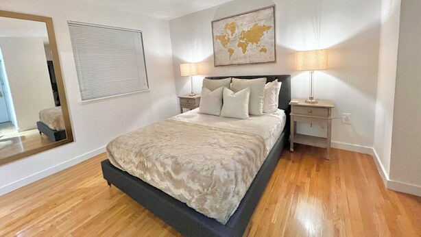 A bedroom with a large bed, two bedside tables, a world map on the wall, a mirror, and a window with blinds. - Large and Rare 4-bedroom apartment in amazing New York with WiFi, AC (New York)