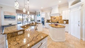 A spacious kitchen with granite countertops, white cabinetry, and a large island.