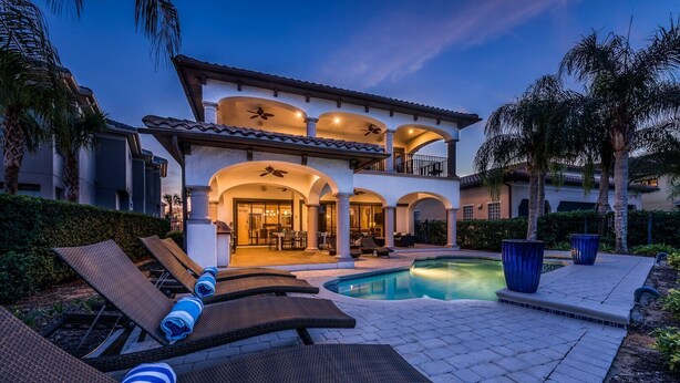 A luxurious house with a swimming pool, outdoor seating, and a covered patio area.