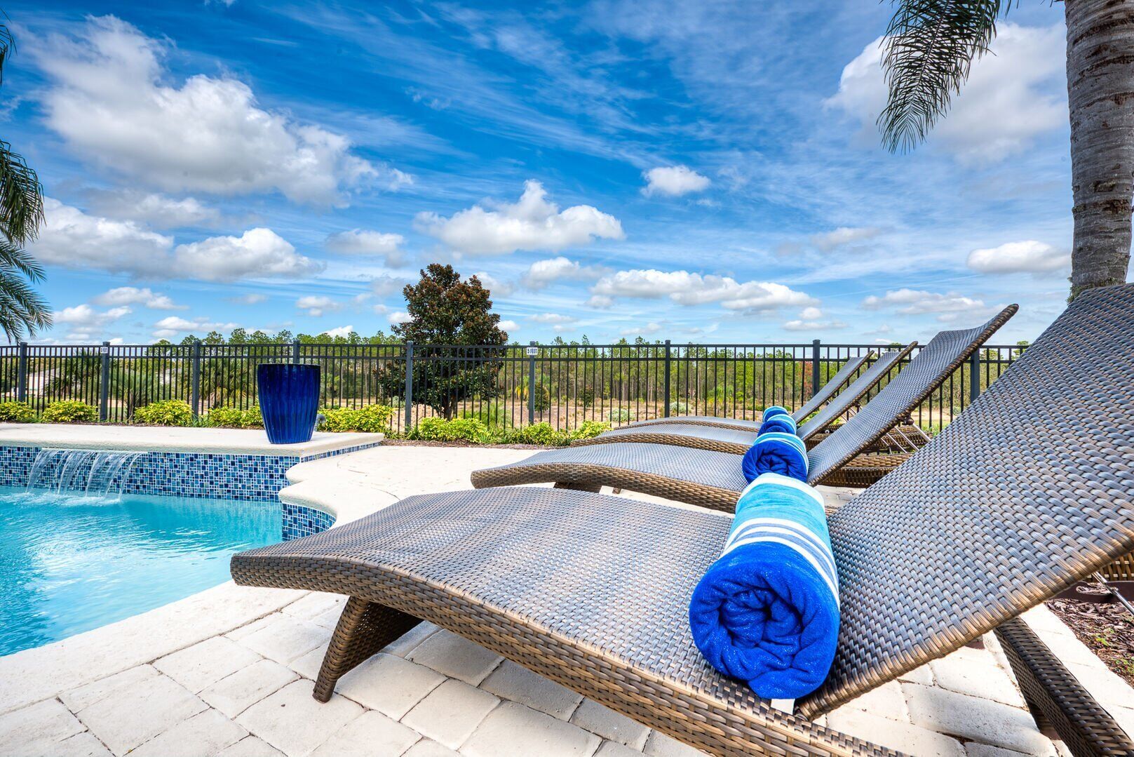 A poolside area with lounge chairs and a blue decorative planter.