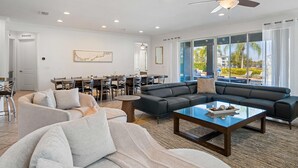 Una sala de estar amplia con un sofá modular grande, una mesa de centro y un comedor con mesa y sillas.