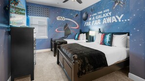 Un dormitorio con temática de Star Wars, que incluye vinilos en la pared y una cama con almohadas con motivos galácticos.