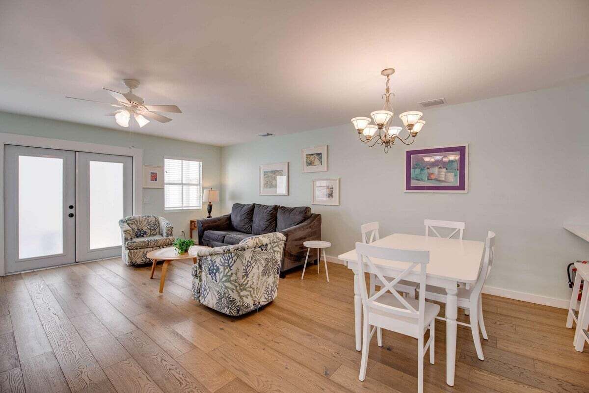 Un salon doté d’un ventilateur de plafond, d’un canapé, d’une table basse, d’une table à manger avec des chaises et d’un lustre.