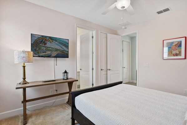 Une chambre à coucher avec un lit, un bureau avec une lampe, une télévision et une armoire.