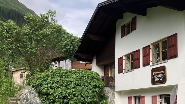 A two-story building with a stone wall and a sign that reads "Susanne."