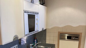 A compact kitchen with a built-in microwave, a sink, and a dishwasher.