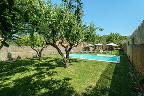 Un jardin avec une piscine, des arbres et une clôture.