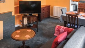 Un salon avec un téléviseur, une table à manger et un canapé.