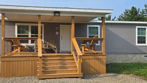 Een huis met twee verdiepingen, een houten veranda, een voordeur en een trap naar de bovenverdieping.