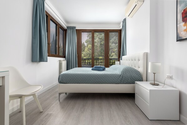 Una camera da letto con un letto, un comodino, una sedia e una finestra con tende.