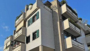 A multi-story building with balconies, a stone facade, and a black fence in the foreground. - La Casa del Tomo - Metro A - Private Parking - 6 Guests (Roma)