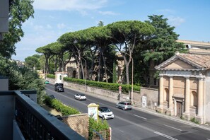 A street with cars, trees, and a building with columns.