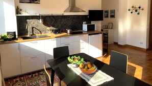 A modern kitchen with a microwave, kettle, and sink. There is a dining table with a fruit bowl and chairs. - Cozy apartment for two to four people near the Auditorium in Rome (Roma)