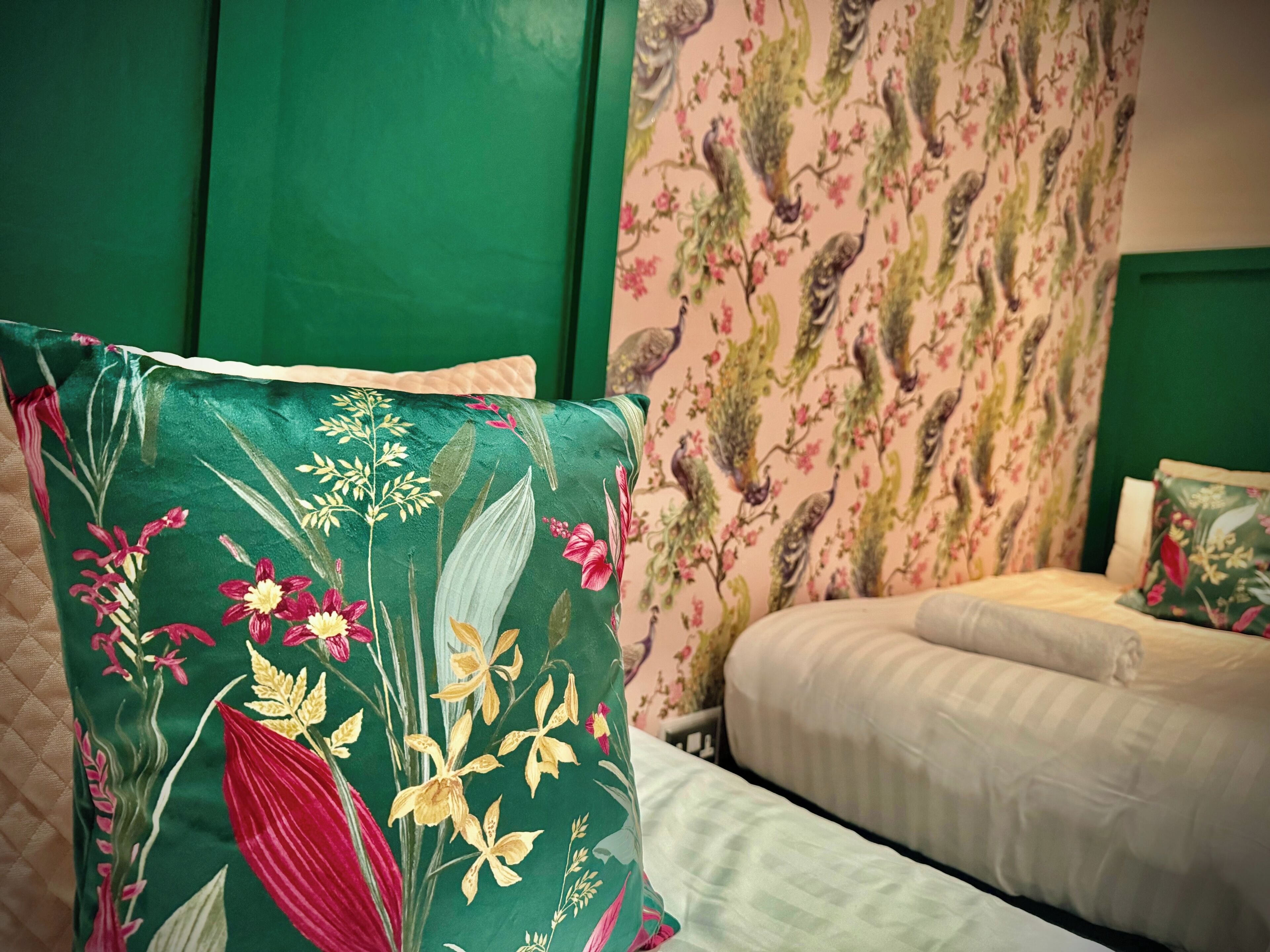 A bed with a floral-patterned pillow and a green headboard.
