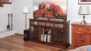 Ein Wohnzimmer mit Fernseher auf einer Holzkommode, Kamin und Bücherregal.