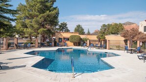 Ein rechteckiger Pool mit Sprungbrett, umgeben von Liegestühlen und einem Zaun.