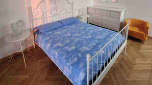 A bedroom with a bed, a small round table, a dresser, and a chair. - Independent Penthouse in the Heart of Modena (Modena)