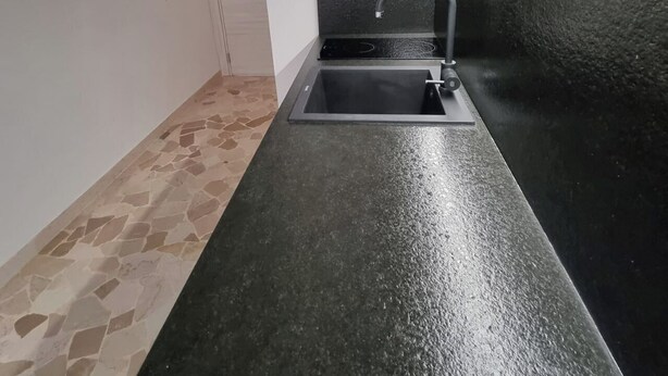 A small kitchen with a single sink, a stove, and a door. - Independent Penthouse in the Heart of Modena (Modena)