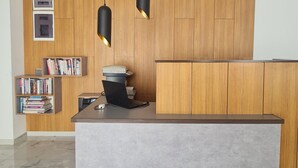 Un comptoir d’accueil moderne avec un dessus gris, un lambris en bois sur le mur et deux suspensions lumineuses.
