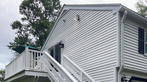 A white house with a wooden staircase leading to a porch.