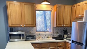 A kitchen with wooden cabinets, a stainless steel refrigerator, a microwave, a toaster oven, and a sink.