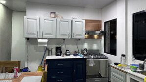 Une cuisine moderne avec des meubles blancs, une cuisinière encastrée et une fenêtre équipée de stores.