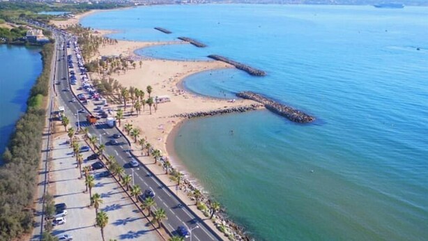 Une route côtière bordée d’une plage et d’un parking.