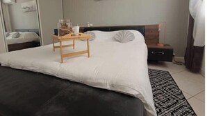 Une chambre à coucher moderne avec un grand lit, une table de chevet et un miroir.