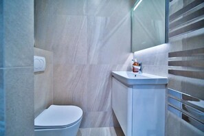 Un baño moderno con inodoro, lavabo y dispensador de desinfectante para manos.