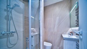 A modern bathroom with a glass shower enclosure, a white toilet, and a sink with a mirror. - Port of Nice - Scooters Included (Nice)