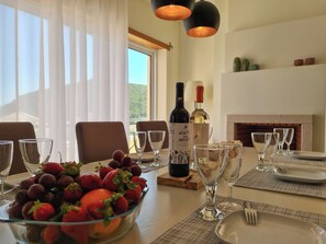 Una mesa de comedor dispuesta con copas de vino, un frutero y botellas de vino.