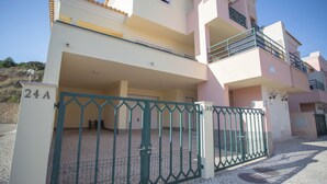 A multi-story residential building with balconies, a gated entrance, and a tiled pavement. - Gorgeous 4-bedroom apartment in Sesimbra with stunning ocean views (Sesimbra)