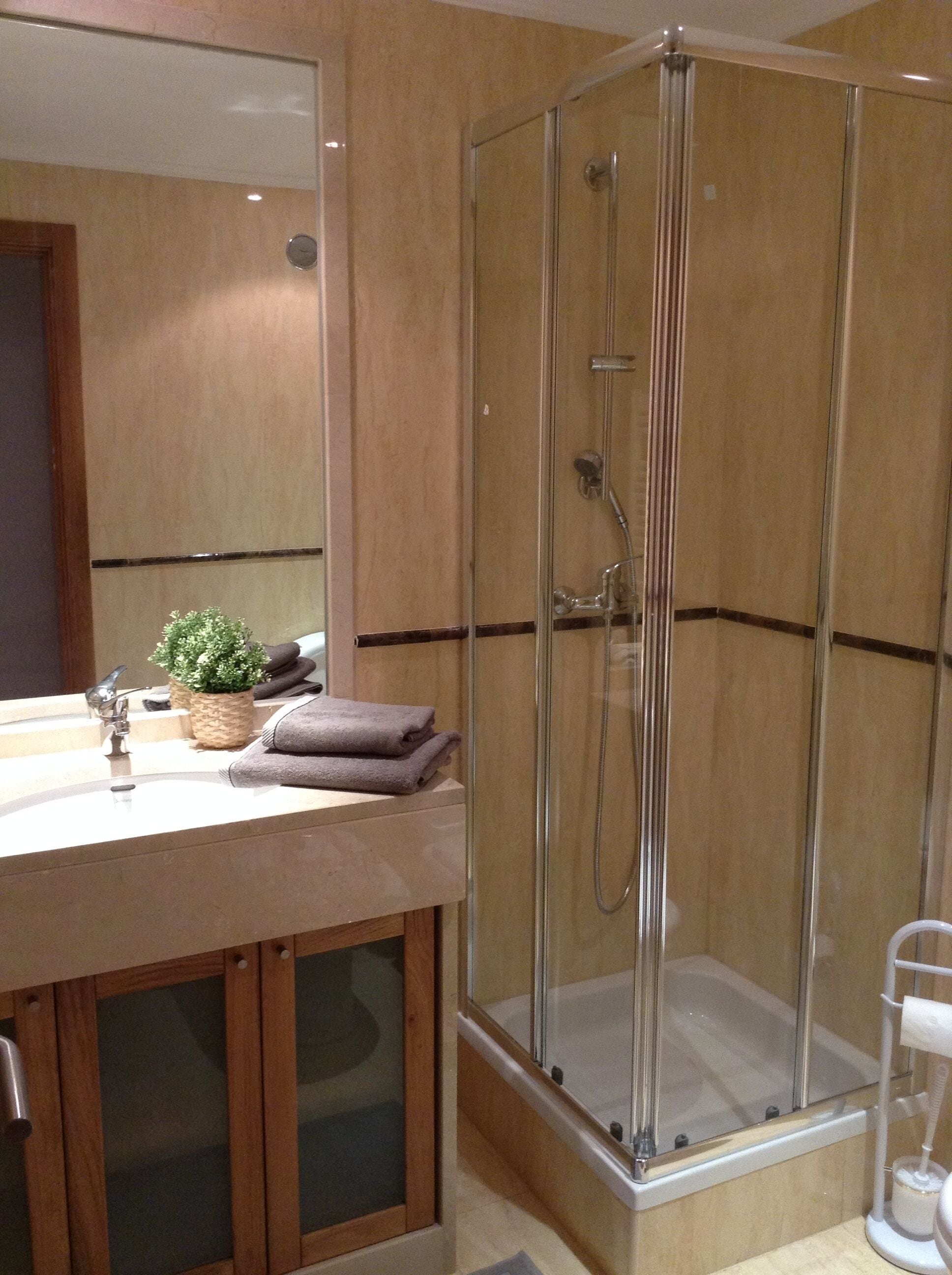 A modern bathroom with a glass-enclosed shower, a wooden vanity with a sink, and a mirror above it.