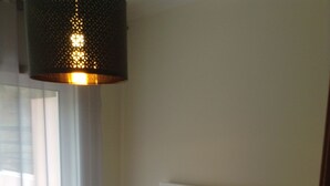A bedroom with a large bed, a bedside table, a lamp, and a hanging light fixture. - Gorgeous 4-bedroom apartment in Sesimbra with stunning ocean views (Sesimbra)