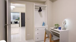 Un dormitorio con un armario blanco, un escritorio con un espejo y una silla.