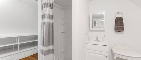 A bathroom with a shower, a vanity with a mirror, and a towel rack.