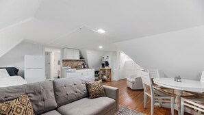 Een modern loft appartement met een vide, een grijze bank, een eettafel en een keuken.