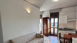 A living room with a sofa, a dining table with chairs, a kitchen area with cabinets, and a stone-tiled floor. - Mantua Palace (Cremona)