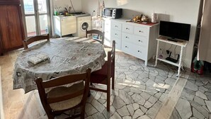 A compact kitchen with a dining area, a TV, and a stone-tiled floor. - Mantua Palace (Cremona)