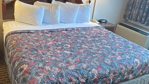 A hotel room with a bed, a nightstand, a lamp, a framed picture, and a window with curtains.