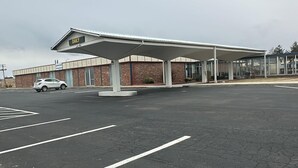 Une station-service dotée d’un auvent, d’un bâtiment en briques et d’une voiture sur le parking.