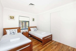 Une chambre avec deux lits en bois, une fenêtre donnant sur un beau paysage et une porte blanche.
