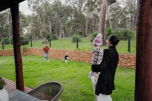 An outdoor area with a stone wall, grass, and trees. - Redgum Treehouse - Luxury home in wine country! (Western Australia)