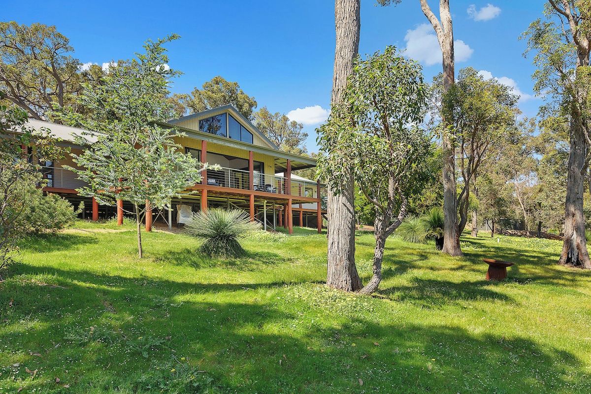 A two-story house with a balcony, surrounded by trees and grass.