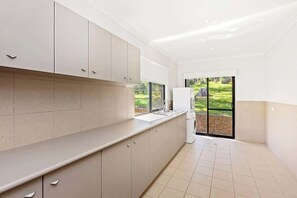 Een moderne keuken met een groot raam, een inbouwoven en een spoelbak.