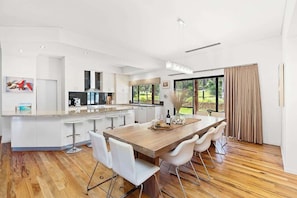 A modern kitchen with a central island, bar stools, and a dining table with chairs.