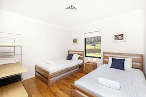 Een kamer met twee bedden, een bureau en een raam met uitzicht op bomen.